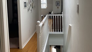 A staircase with a white railing, a skylight, and a hallway with framed pictures on the walls. - Clean house in great neighbourhood! (Toronto)