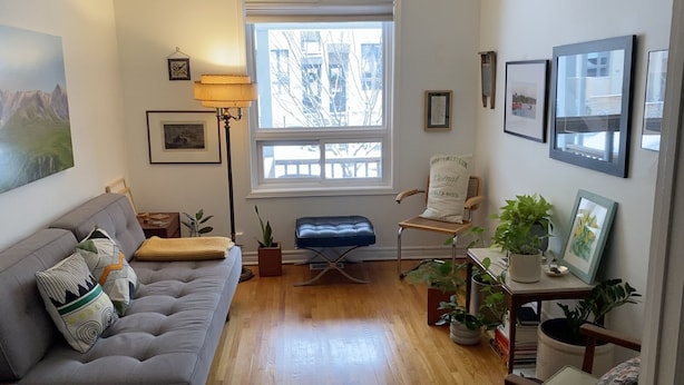 A cozy living room with a grey sofa, a blue armchair, and a wooden coffee table. There are several framed pictures on the walls and a window with a view of the outside. - Clean house in great neighbourhood! (Toronto)