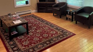 A living room with a TV, a red patterned rug, a sofa, and two armchairs. - Lovely condo right beside Acadia (Bar Harbor)