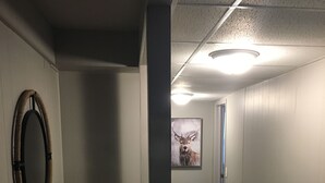 A hallway with a wooden bench, a framed deer picture, and a door at the end. - The Superior Lodge - Located On Trail - Pictured Rocks Lakeshore, Munising MI (Munising)