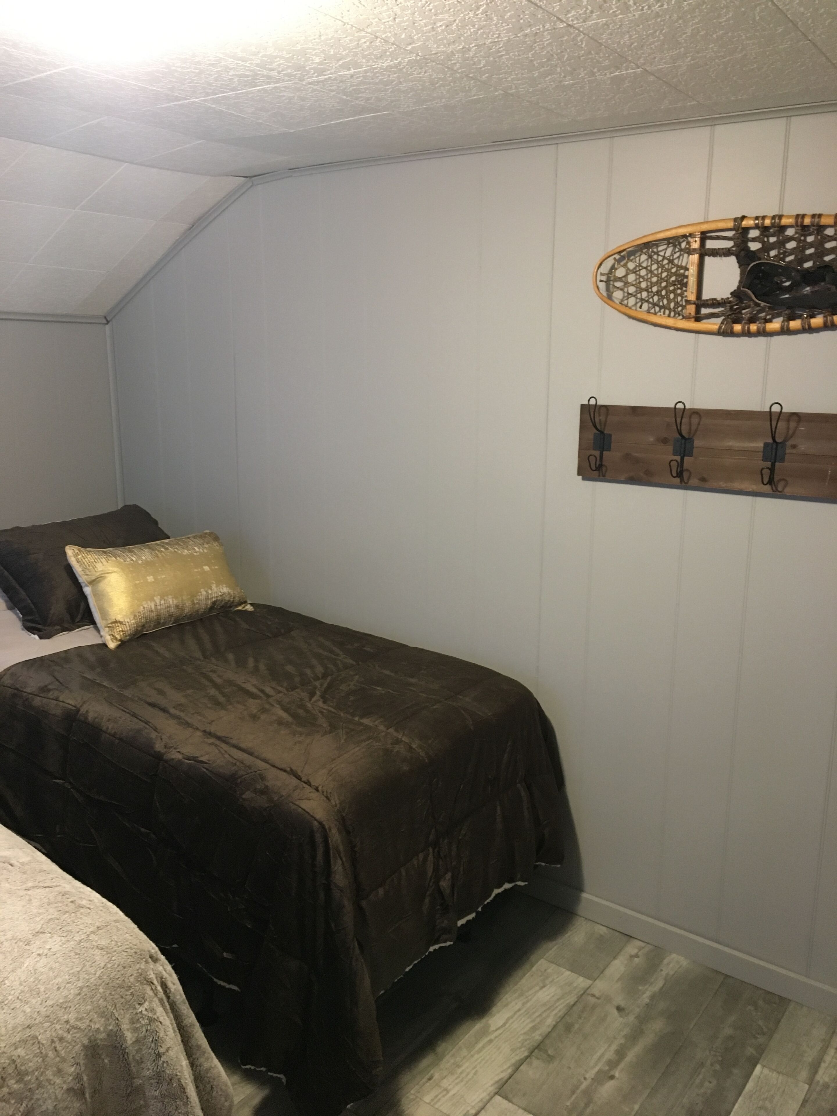Un dormitorio con cama, estante en la pared y ventilador de techo.