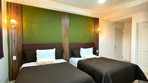 A hotel room with two beds, green walls, wooden paneling, and recessed ceiling lights. - Royal Madero Inn Express (Tampico)