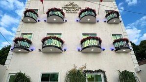 A multi-story hotel with balconies adorned with red flowers, large windows, and a clear sky. - Royal Madero Inn Express (Tampico)