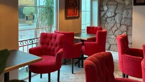 A dining area with red upholstered chairs, black pendant lights, and a stone wall. - Royal Madero Inn Express (Tampico)
