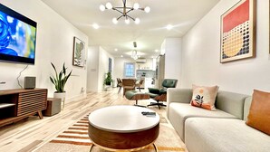 Ein modernes Wohnzimmer mit rundem Couchtisch, einem grauen Sofa und einem flachbildfernseher an der Wand.