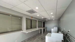 A laundry facility with multiple washing machines, a long counter, and a tiled floor. - Studio 6 Ogden, Ut – 21St Street (Ogden)