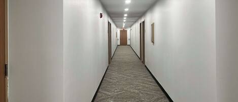 A long, narrow hallway with white walls and a patterned carpet.