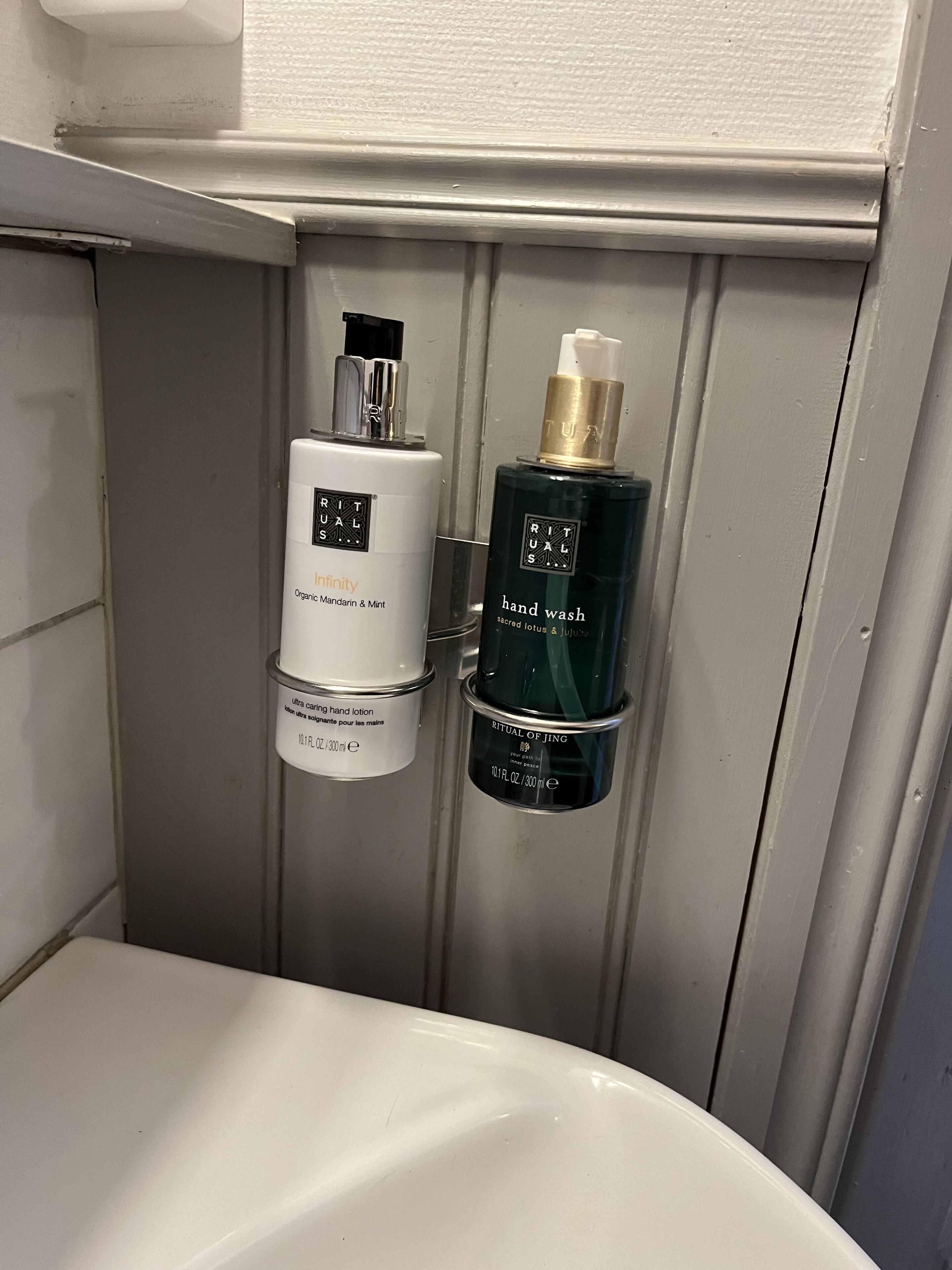 A bathroom with a white sink, two bottles of hand wash, and a white toilet.