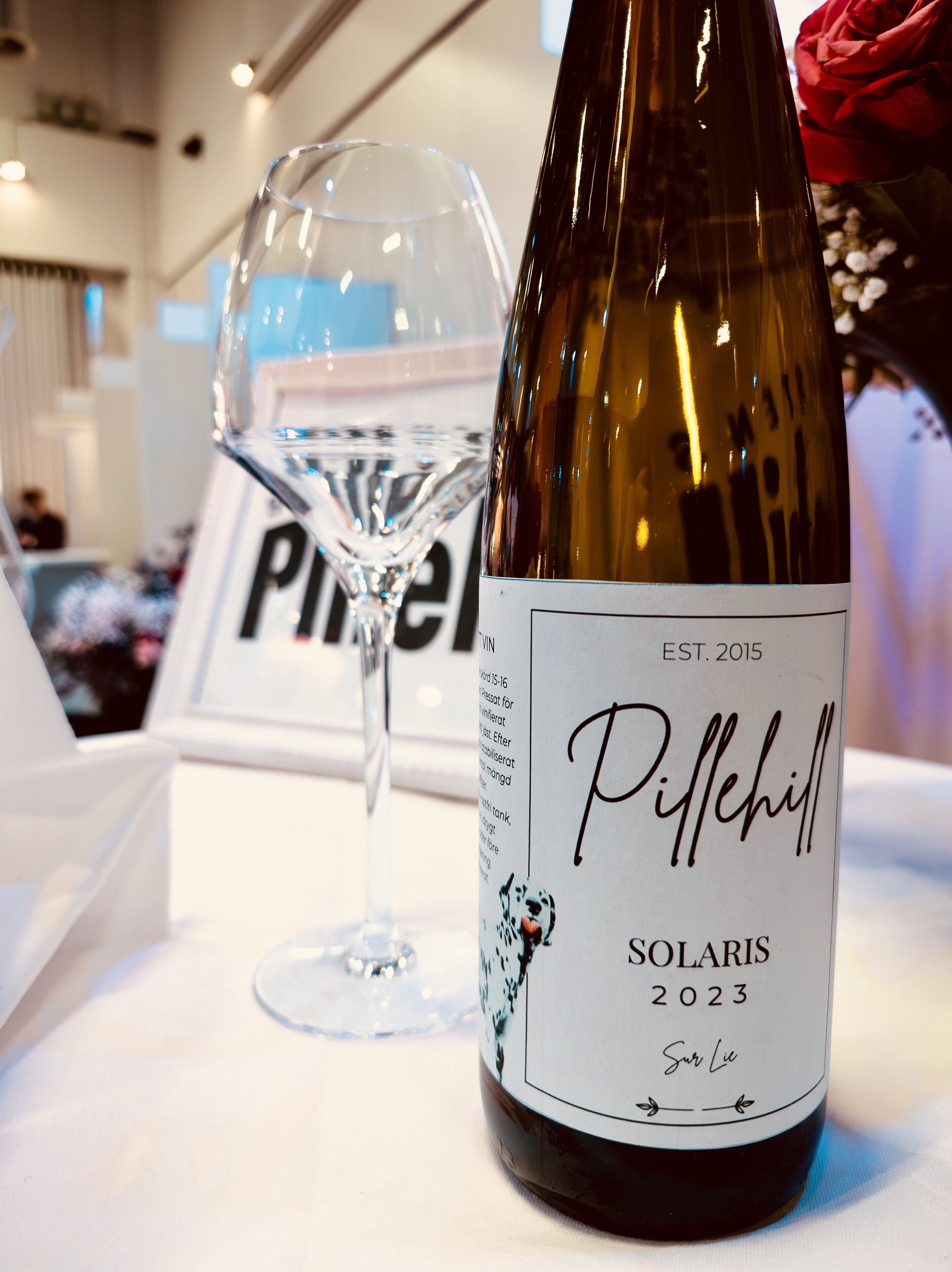 A wine bottle labeled 'Pillehill Solaris 2023' and a wine glass on a table.