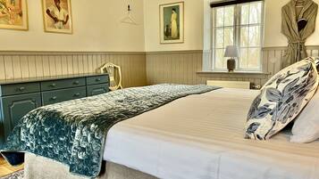 A bedroom with a bed, dresser, window, and artwork on the wall.