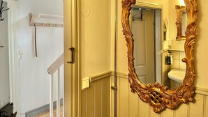 A room with a large ornate mirror, a door with a brass handle, and a white door frame.