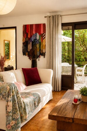 A living room with a sofa, a wooden table, a wall with a tie collection, and a sliding glass door leading to an outdoor area. - House LA VILLANELLE: swimming pool, pétanque, quiet in the beautiful town of Uzès (Uzès)