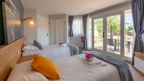 Quarto de hotel com duas camas, uma janela grande e vista para a área externa.