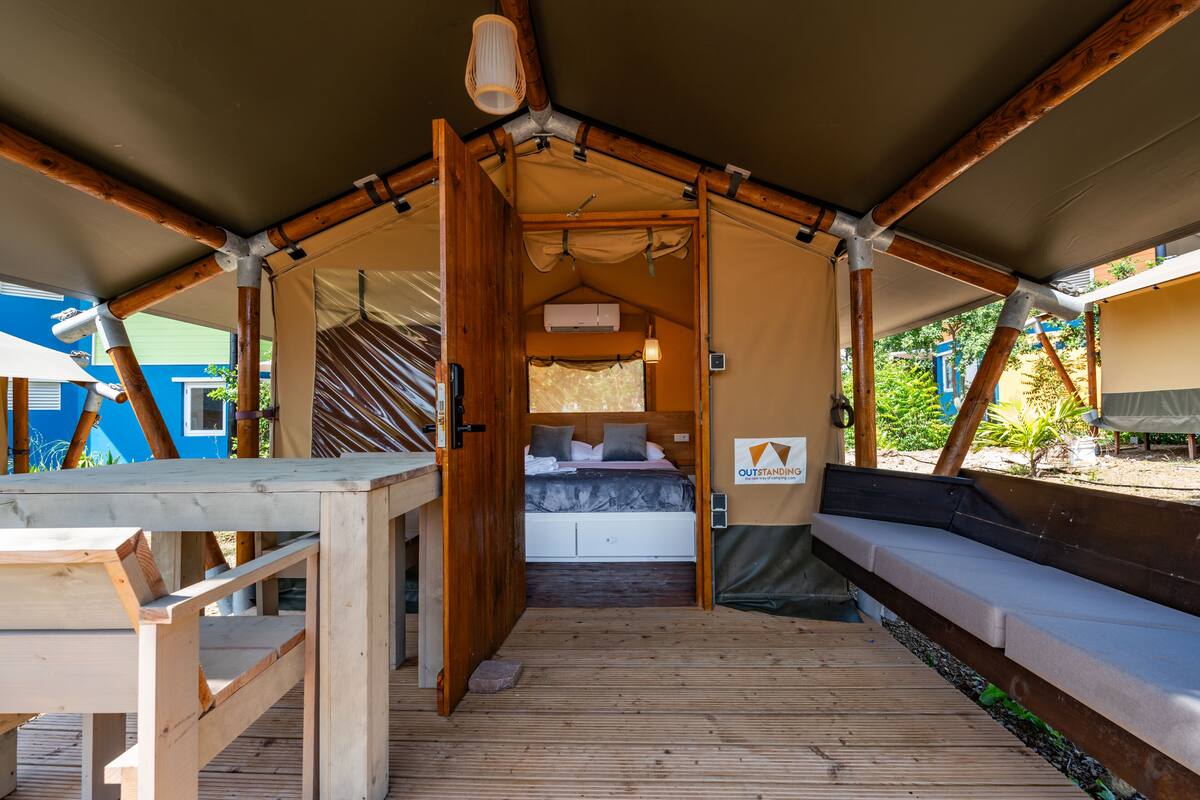 Alojamiento con tiendas de campaña, una cama, muebles de madera y vistas al exterior.