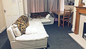 A living room with a sofa covered in a leopard print blanket, a dining table, and a fireplace. - Beautiful 1-bed House in Leeds (Leeds)