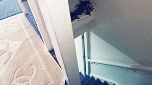 A staircase with a handrail, a white wall, and a small plant on the landing. - Beautiful 1-bed House in Leeds (Leeds)