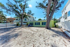A residential area with a sandy yard, a tree, and a building with large windows. - Sunrise Vista (Anna Maria)
