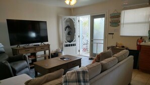 Ein Wohnzimmer mit Fernseher, Sofa, Couchtisch und einer Tür mit dekorativem Glasfenster.