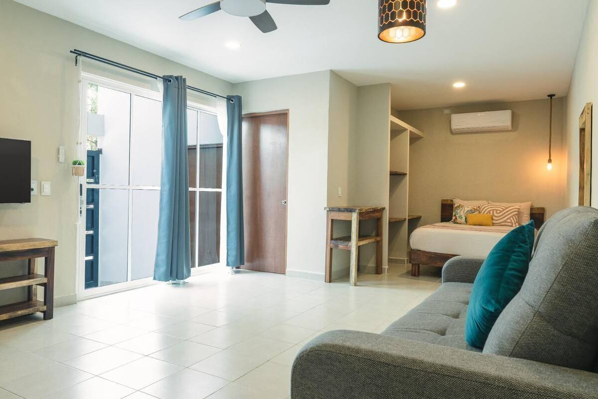 Een moderne woonkamer met een bank, een bijzettafeltje, een plafondventilator en een schuifdeur naar een balkon.