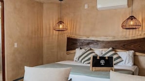 Ein Schlafzimmer mit einem Bett, zwei Stühlen, einem Tisch mit einer Flasche und Gläsern sowie einer Klimaanlage.