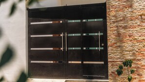 Ein modernes Gebäude mit einem schwarzen Metallgitter, einer Steinsäule und einer kleinen Pflanze.