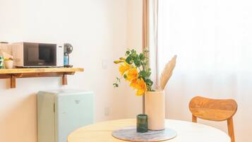 A modern kitchen with a microwave, a small refrigerator, and a wooden dining table with chairs.