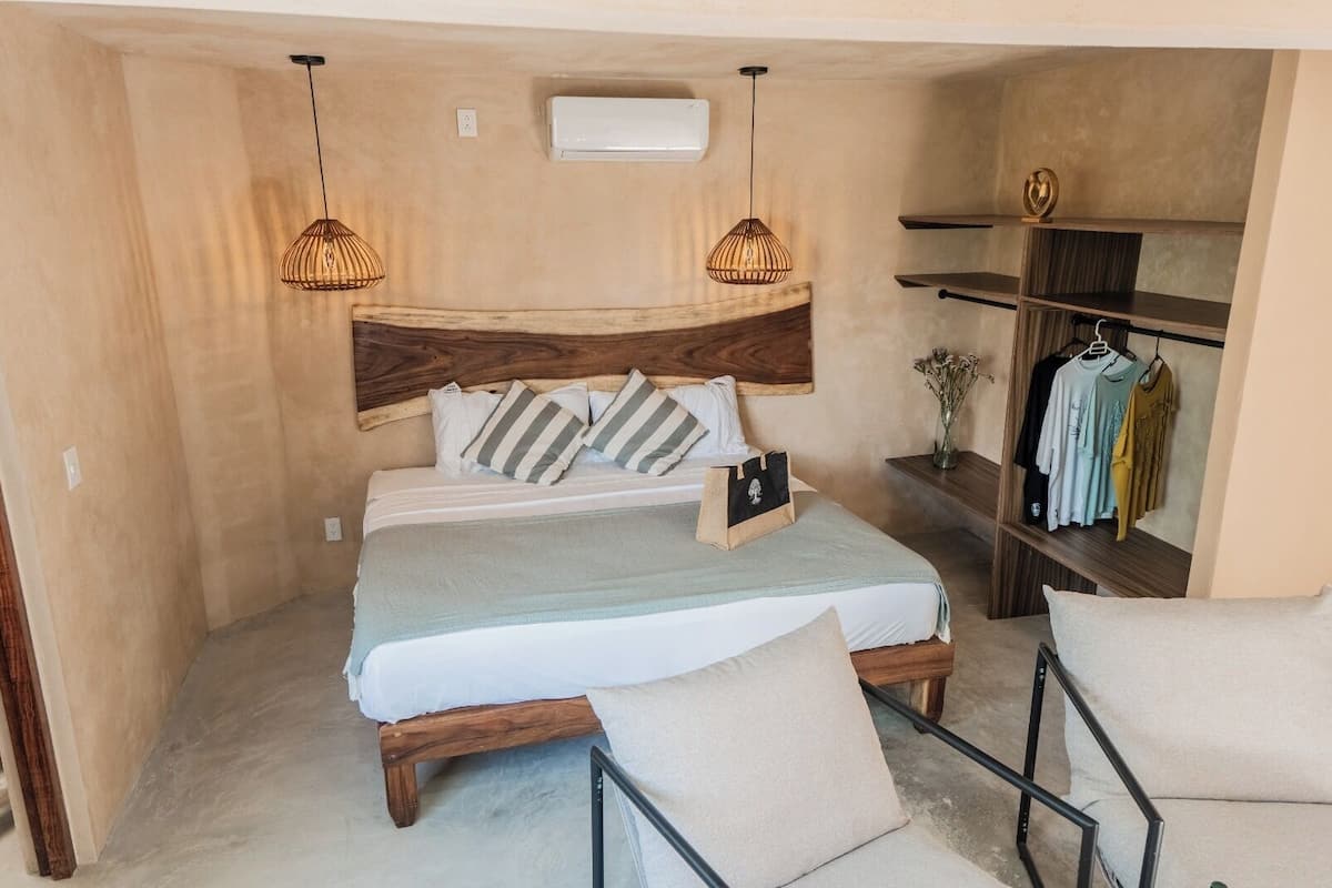 Een slaapkamer met een houten bed, twee bedlampen, een nachtkastje, een kledingrek en een klein plankje.