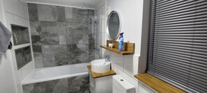 Et moderne badeværelse med bruser, håndvask og toilet.