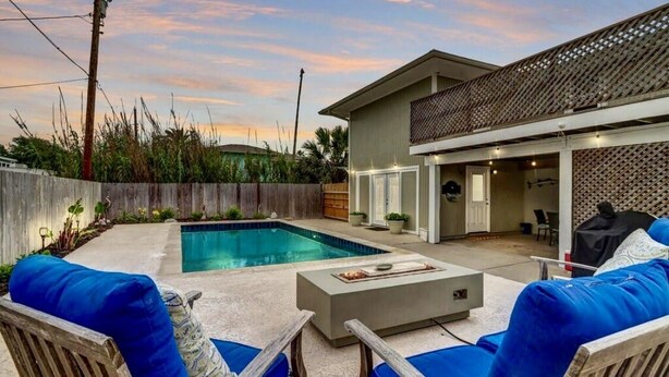 A backyard with a swimming pool, outdoor furniture, and a house with a covered patio area. - Big Beautiful Beach House with private heated pool close to beach & everything! (Port Aransas)