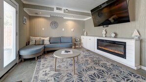 A living room with a sectional sofa, a fireplace, a flat-screen TV, and a patterned rug. - Big Beautiful Beach House with private heated pool close to beach & everything! (Port Aransas)