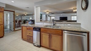A modern kitchen with granite countertops, stainless steel appliances, and wooden cabinetry. - Big Beautiful Beach House with private heated pool close to beach & everything! (Port Aransas)