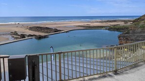 Une vue sur la côte, avec une plage, une zone rocheuse et un ciel dégagé.