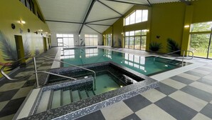 Une piscine intérieure dotée d’un sol à carreaux, entourée de murs jaunes et de grandes fenêtres.