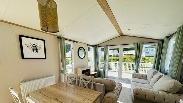 Une pièce chaleureuse avec une table en bois, un canapé beige et une vue sur une terrasse.