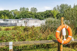 A row of mobile homes with a lifebuoy attached to a fence in the foreground. - Dog Friendly Park 5 Miles From Bude 2 bed Caravan (Holsworthy)