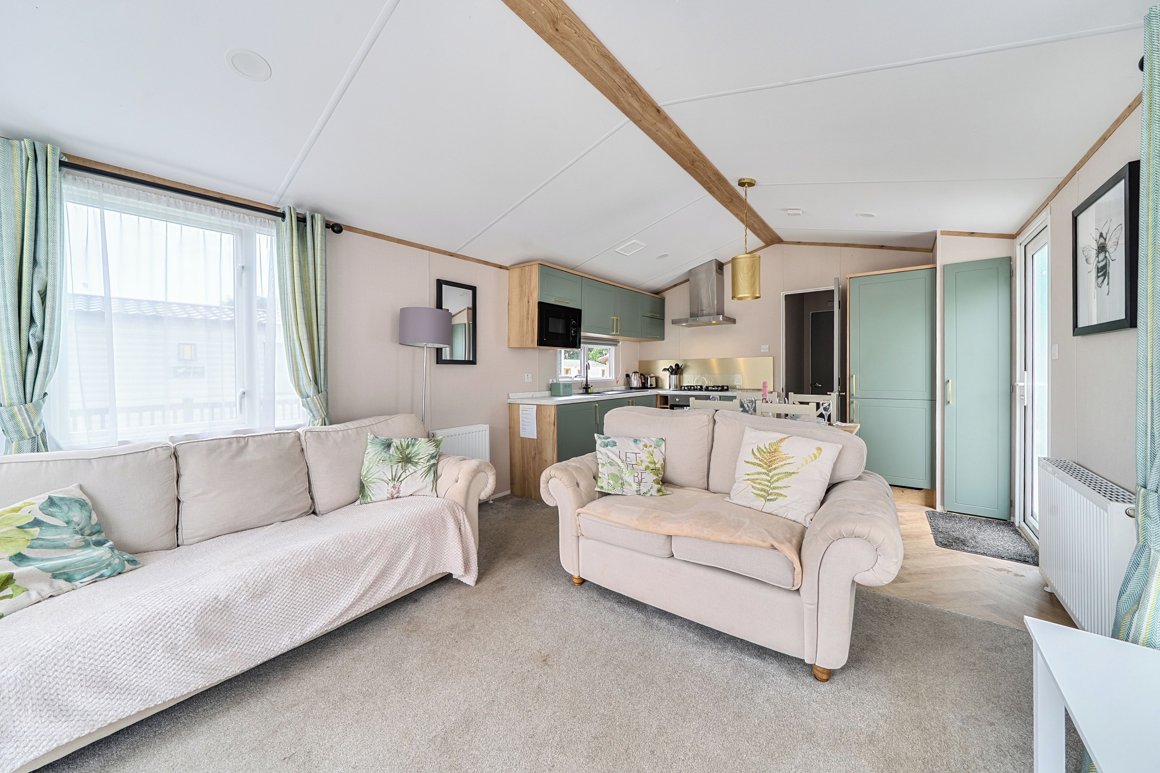 A modern living room with a sofa, a smaller couch, and a kitchen area in the background.