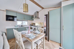 Une cuisine compacte avec un coin repas, comprenant un four à micro-ondes, un évier et un luminaire suspendu.