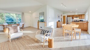 Amplia sala de estar con mesa de comedor de madera, un sofá y un ventanal con vistas a la vegetación.