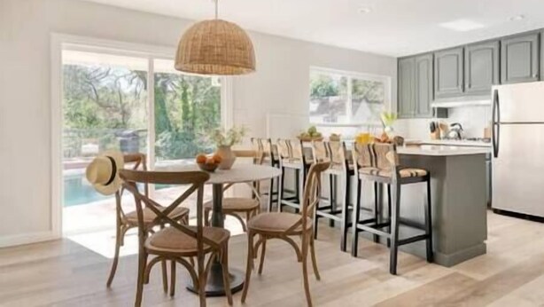 A modern kitchen with a central island, dining area with chairs, and a view of the outdoors. - Spacious 5BR/3BA Group Getaway, Pool & EV Charger (Santa Rosa)