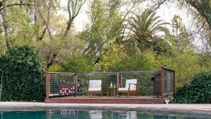 A poolside area with a fenced deck, two chairs, and a small table. - Spacious 5BR/3BA Group Getaway, Pool & EV Charger (Santa Rosa)