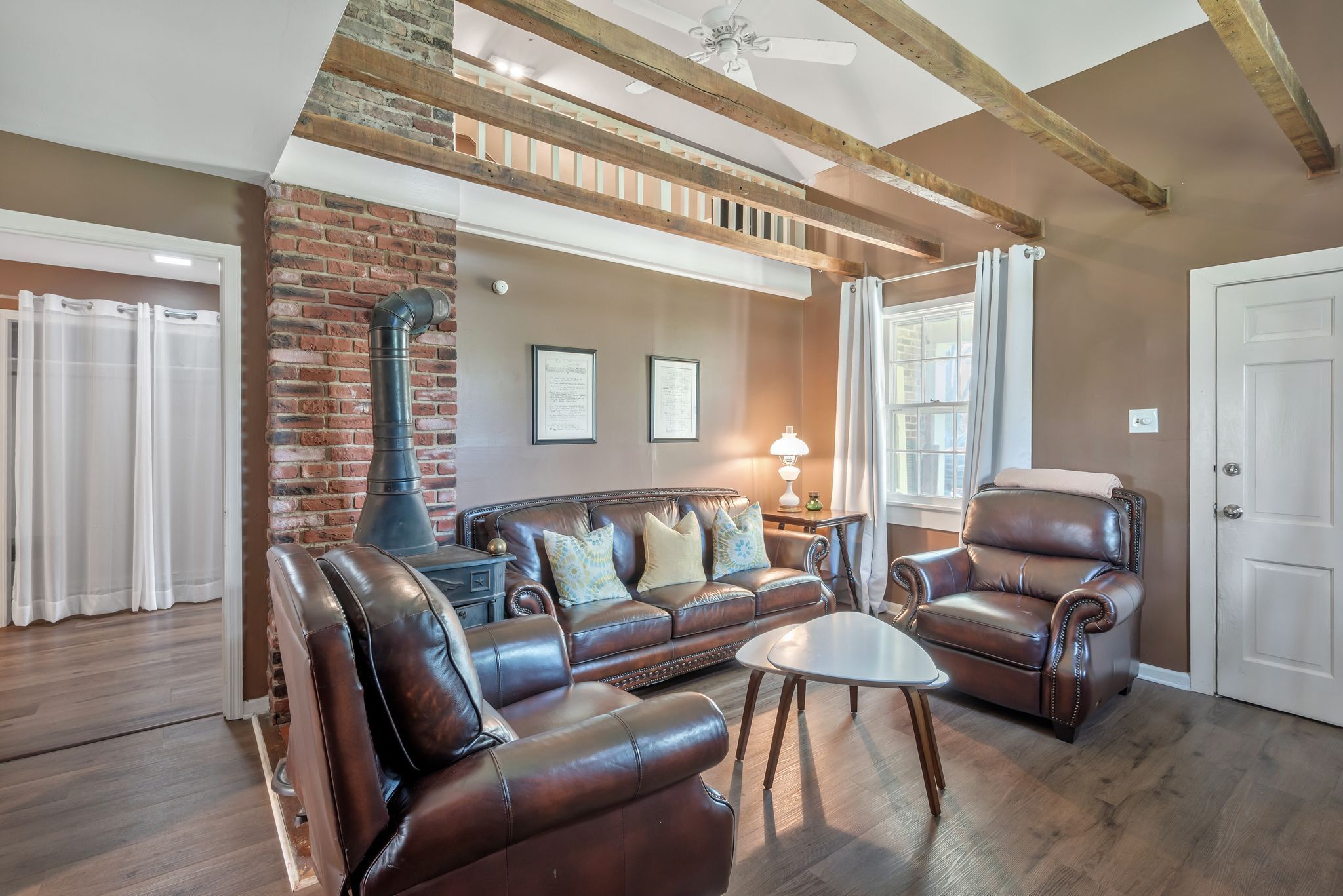 A spacious living room with leather sofas, a coffee table, and a fireplace.