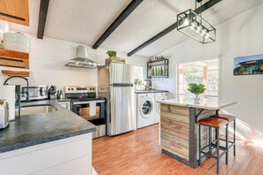 A modern kitchen with a central island, stainless steel appliances, and a bar area with wine bottles. - Awesome Canyon Lake Home: Rooftop Deck & Fire Pit! (Canyon Lake)