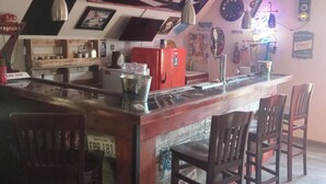 A bar area with a counter, chairs, and various decorations including Bud Light banners. - Beautiful retreat with gameroom and outdoor grill. (Myrtle Beach)