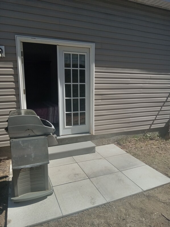 A house with a sliding glass door, a barbecue grill, and a concrete patio. - Beautiful retreat with gameroom and outdoor grill. (Myrtle Beach)
