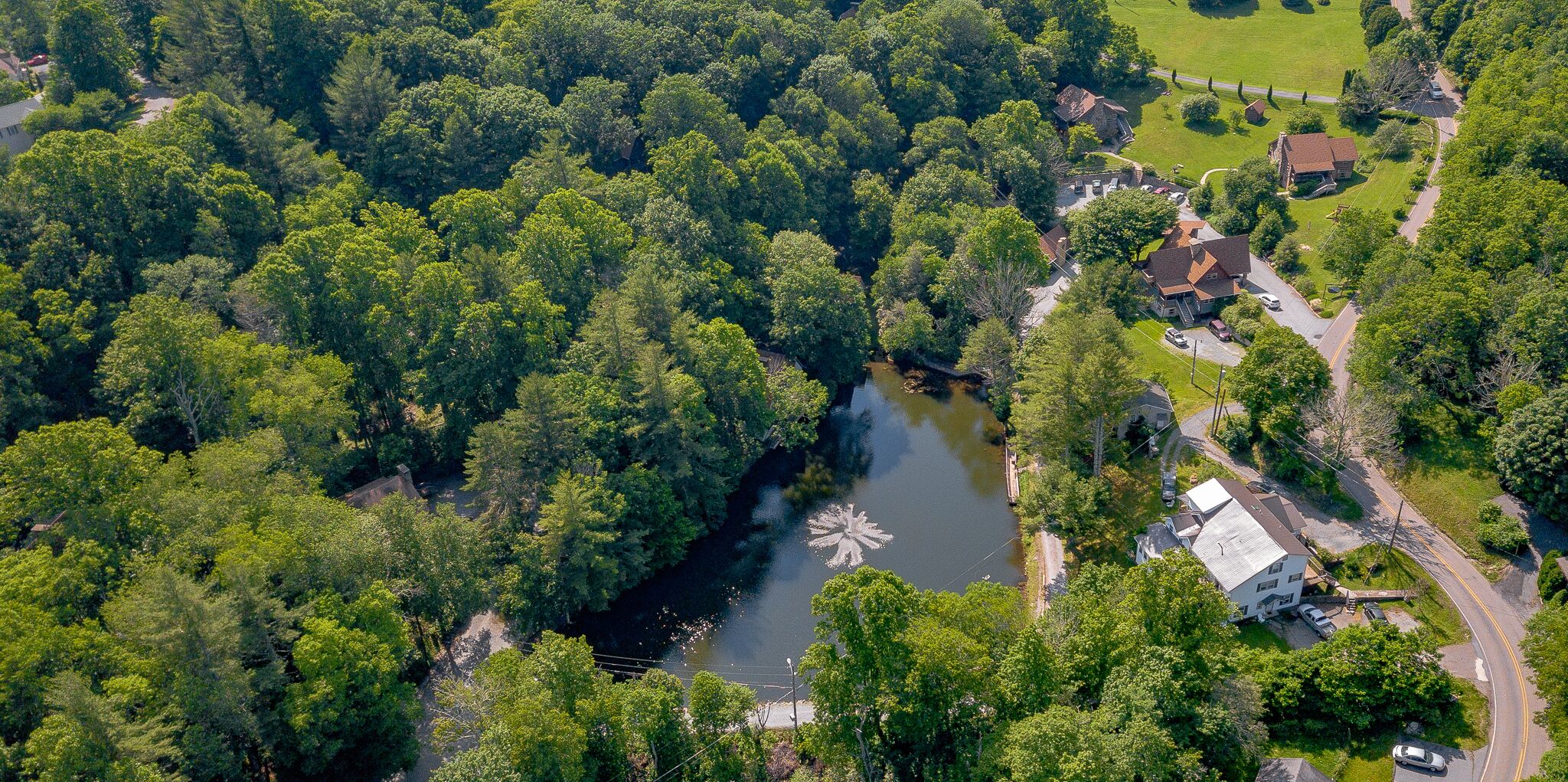Vista aérea de una zona residencial con un río, casas y un parque.