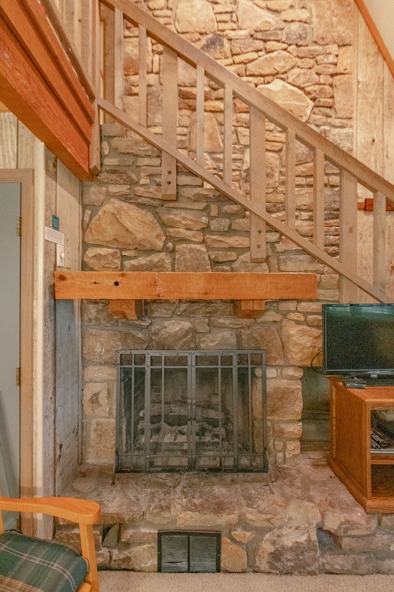 A stone fireplace with a wooden staircase leading up.