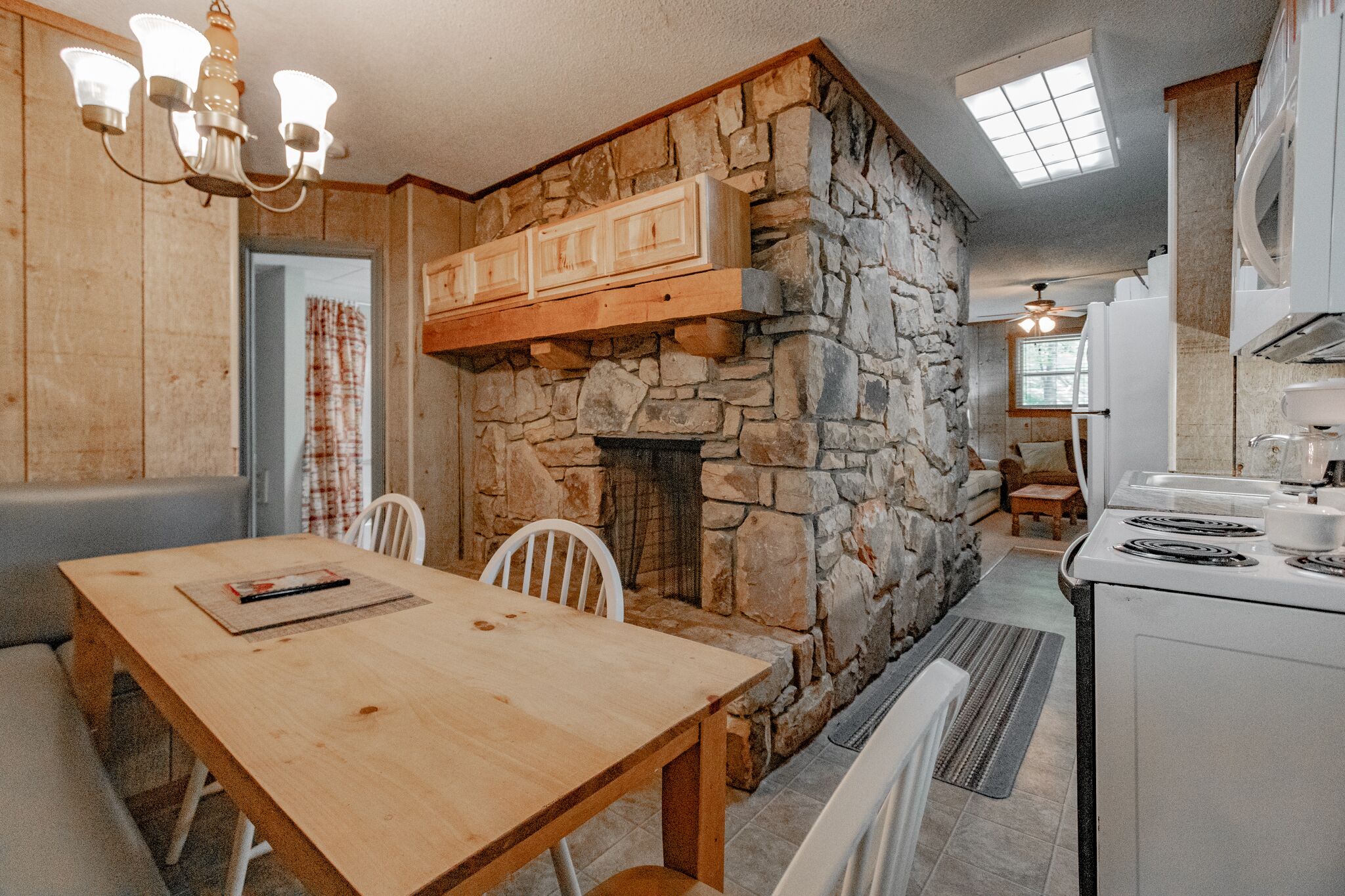 A cozy kitchen with a stone wall, wooden cabinets, and a dining area with a table and chairs.