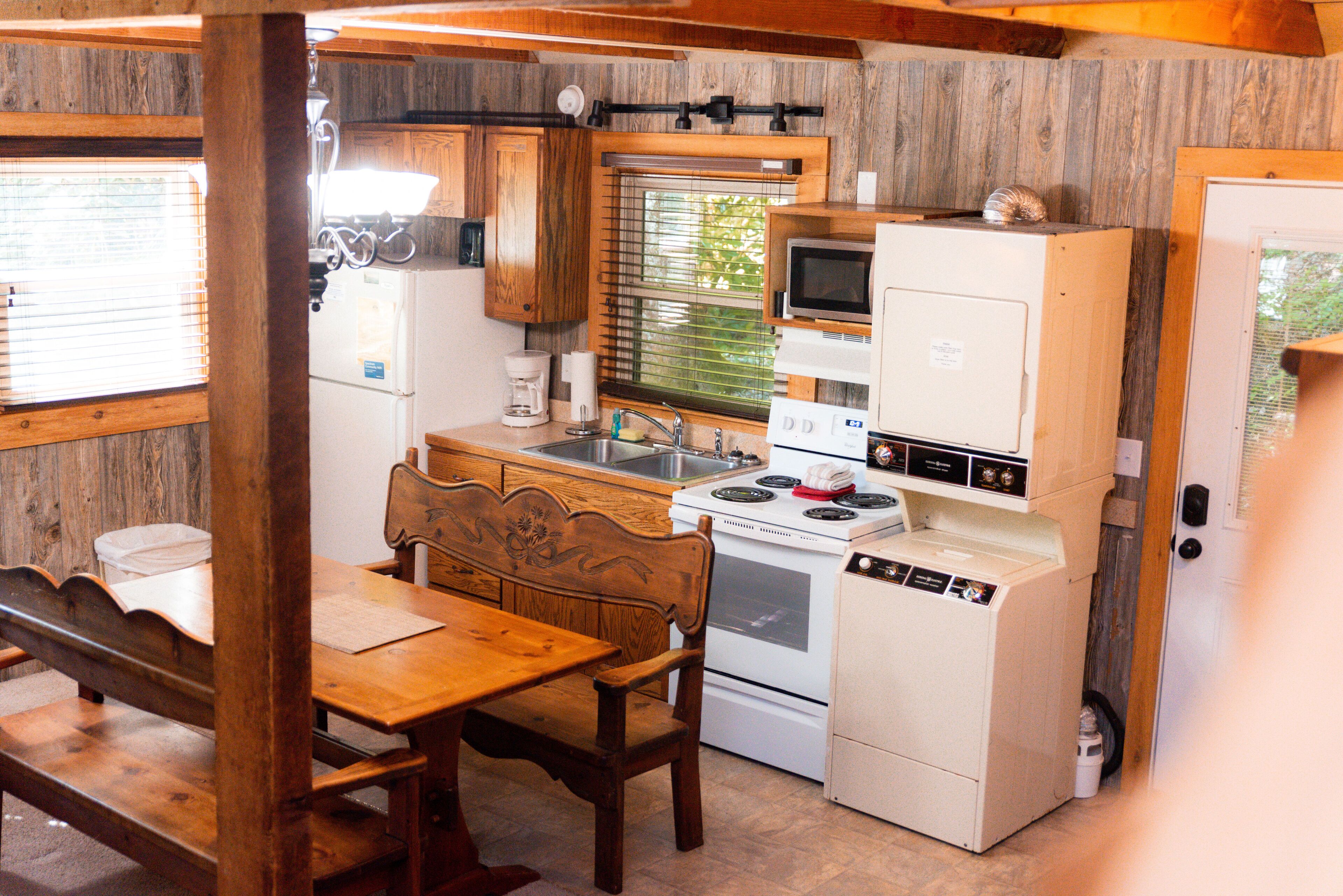 A compact kitchen with wooden cabinetry, a built-in microwave, a stove, and a sink.
