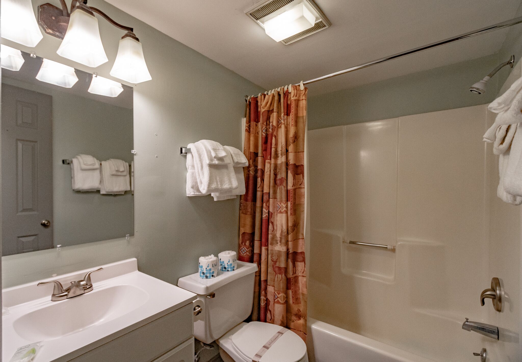 A bathroom with a sink, toilet, and shower. There are towels hanging on the wall and a shower curtain.