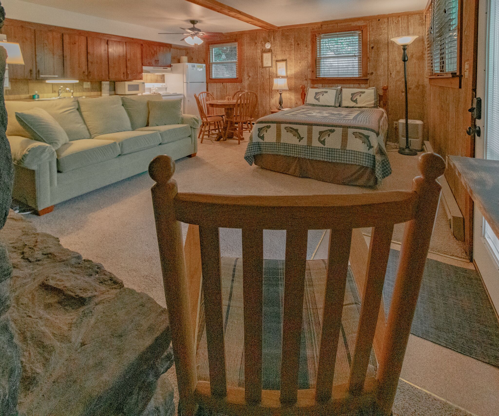 A cozy room with a bed, a sofa, a dining table, and a kitchen area.